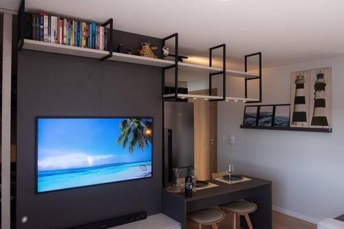 ein Wohnzimmer mit einem Flachbild-TV an der Wand in der Unterkunft Studio perfeito no Parque Una com vaga de garagem in Pelotas