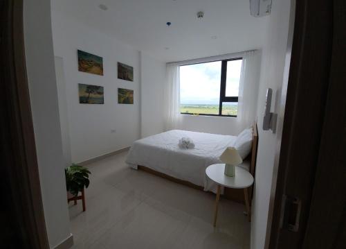 a white bedroom with a bed and a window at Thỏ homestay, căn hộ cao cấp Huế in Hue