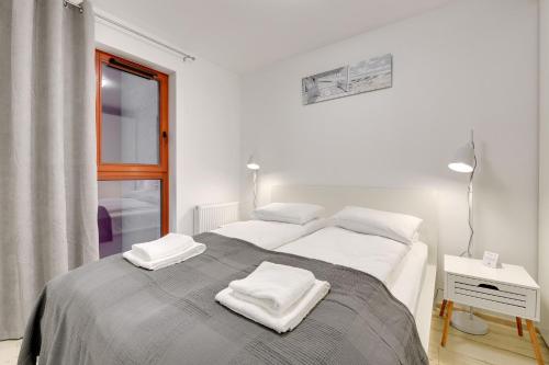a bedroom with a large bed with two white towels on it at Flatbook - City Center SPA Apartments Waterlane Island in Gdańsk