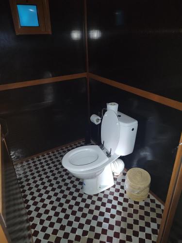a bathroom with a white toilet in a black wall at Rimal Luxury Camp in Merzouga