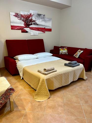 una camera con un letto e un divano rosso di Tutti i Comfort Giuliano's Apartment a Messina