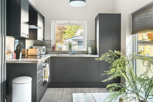 a kitchen with black cabinets and a window at Brand New 1-Bed Flat Steps from Clifton NTU Campus in Nottingham