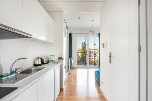 a kitchen with white cabinets and a wooden floor at New Varsovia Comfort 310 in Warsaw