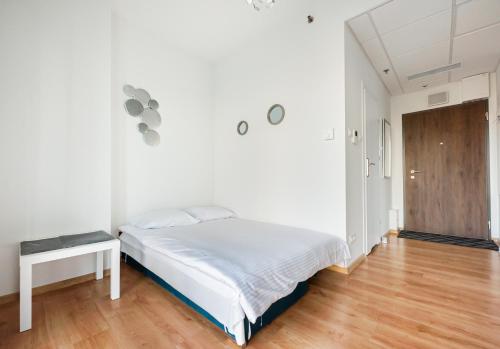 a white bedroom with a bed and a wooden floor at New Varsovia Comfort 310 in Warsaw