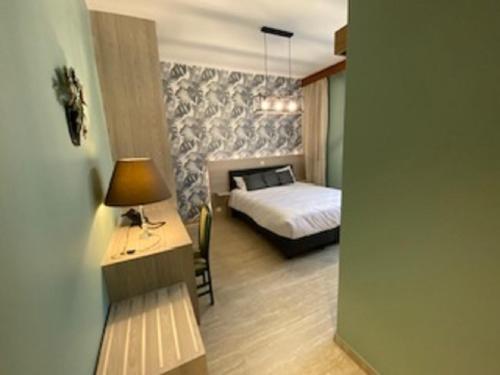 1 dormitorio con 1 cama y escritorio con lámpara en Hotel IL Castellino en Chaudfontaine