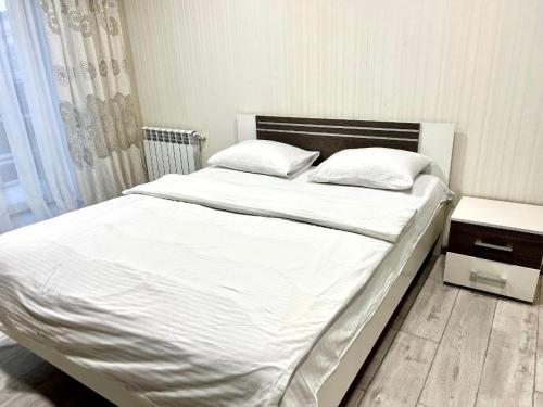 uma cama com lençóis brancos e almofadas num quarto em ApartPoltava 2 ОКРЕМІ кімнати, новобудова, ДВА великих ліжка ЦЕНТР, КОРПУСНИЙ САД em Poltava