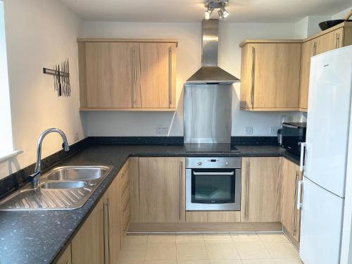 a kitchen with wooden cabinets and a sink and a refrigerator at Travaal.©om - 2 Bed Serviced Apartment Farnborough in Farnborough