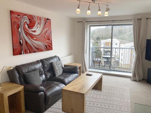 a living room with a leather couch and a table at Travaal.©om - 2 Bed Serviced Apartment Farnborough in Farnborough