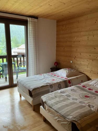 deux lits dans une chambre avec une grande fenêtre dans l'établissement Appartement Capucine, à Chamonix-Mont-Blanc