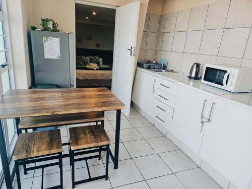 a kitchen with a table and two chairs and a microwave at Sea Breeze Manor - Green Unit in East London