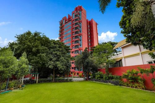 a red building with a park in front of it at Lemon Tree Suites, Whitefield, Bengaluru in Bangalore