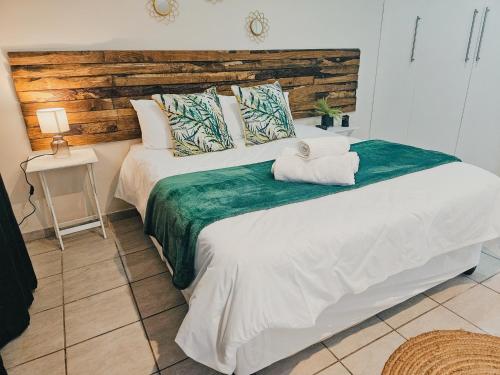 a bedroom with a large bed with a wooden headboard at Sea Breeze Manor - Green Unit in East London