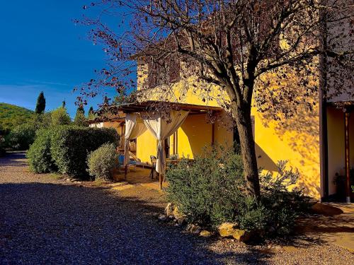 a yellow house with a tree in front of it at Carpine Agriturismo Bio in Maremma in Alberese