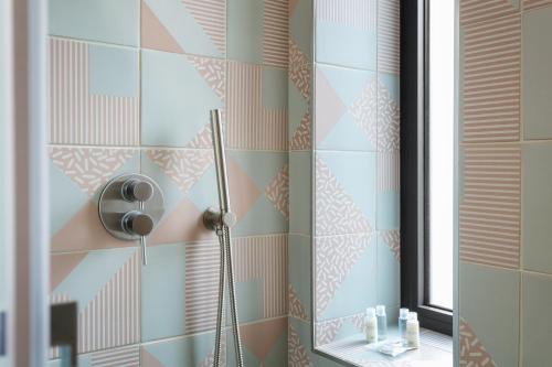 y baño con ducha y azulejos de color rosa y azul. en Double D House, en Olbia