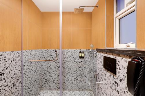 a bathroom with a shower with a glass door at Lemon Tree Suites, Whitefield, Bengaluru in Bengaluru