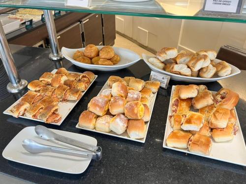 una mesa cubierta con platos de bollería y tazones de pan en Belo Horizonte Plaza, en Belo Horizonte