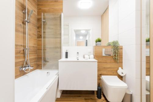 a bathroom with a tub and a toilet and a sink at Nakielska Sesame Premium Apartment in Warsaw
