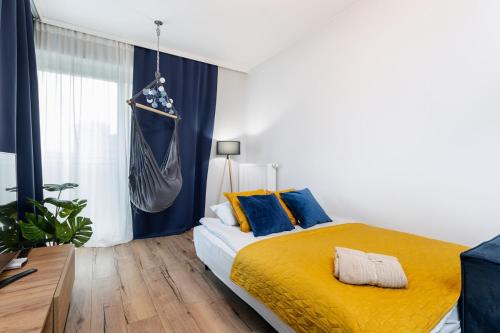 a bedroom with a bed with yellow sheets and blue pillows at Nakielska Sesame Premium Apartment in Warsaw