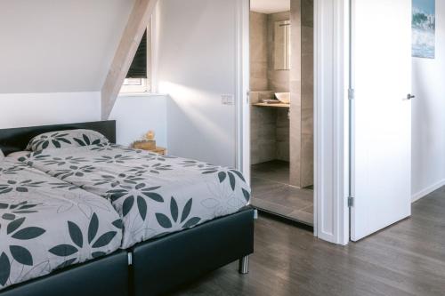 um quarto com uma cama com um edredão preto e branco em Zeeuws Huisje em Serooskerke