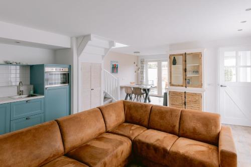 uma sala de estar com um sofá castanho numa cozinha em Zeeuws Huisje em Serooskerke