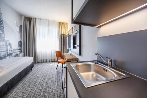 ベルリンにあるホテル リュツォのシンクとベッドが備わるホテルルームです。