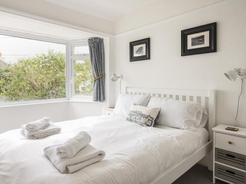 a white bedroom with a bed with towels on it at The Mead in Seaton