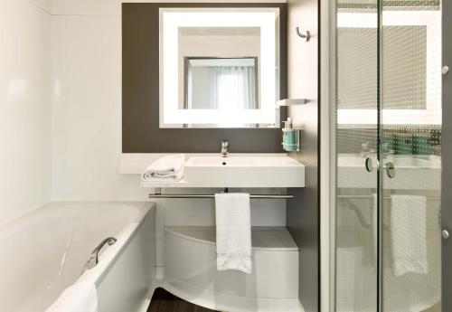 La salle de bains blanche est pourvue d'un lavabo et d'une baignoire. dans l'établissement B&B HOTEL Paris Grand Roissy CDG Aéroport, à Roissy-en-France