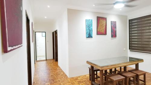 een kamer met een tafel en een aantal schilderijen aan de muur bij The Spring Homestay Apartment in Kuching