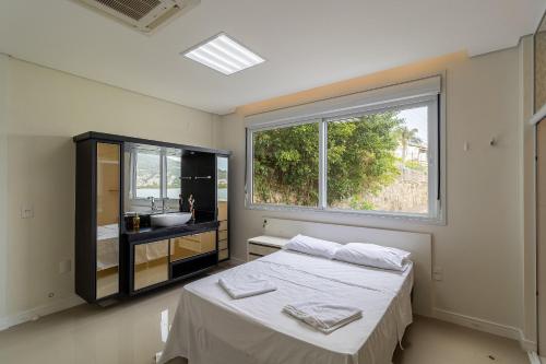 1 dormitorio con cama, lavabo y ventana en Casa à beira-mar com piscina Floripa-SC RJD156 en Florianópolis