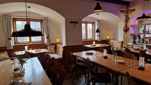 un restaurante con mesas y sillas de madera y ventanas en Hotel Landgasthof Alter Wirt, en Fischbachau