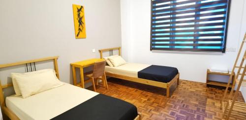 een kamer met 2 bedden, een bureau en een raam bij The Spring Homestay Apartment in Kuching