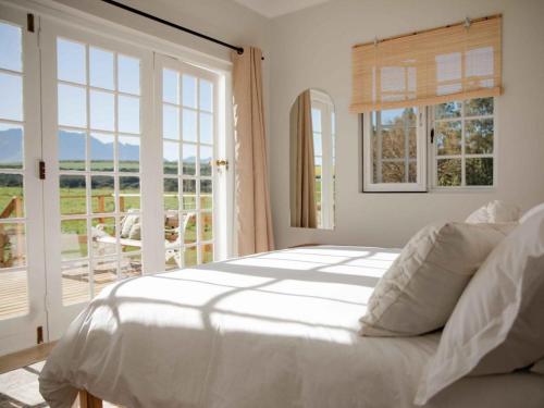 Dormitorio blanco con cama y ventana grande en Melkhout Farm Cottage, en Bonnievale