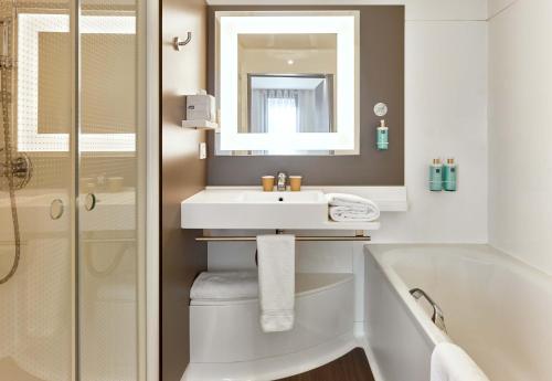 a bathroom with a sink and a tub and a mirror at B&B HOME Rueil-Malmaison Gare in Rueil-Malmaison