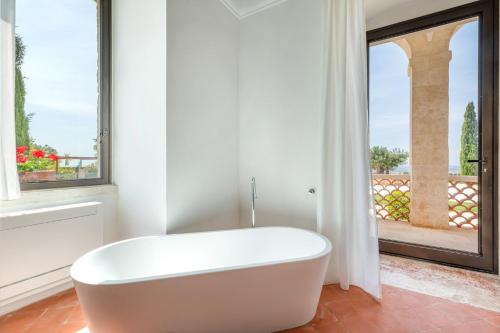 baño con bañera blanca y ventana en Mastropà Exclusive Palace by Raro Villas, en Massafra