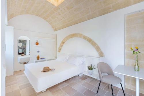 Dormitorio blanco con cama, mesa y silla en Mastropà Exclusive Palace by Raro Villas, en Massafra
