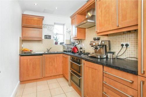 a kitchen with wooden cabinets and a stove top oven at Lovely 1 bedroom flat in Richmond-great location! in Richmond upon Thames