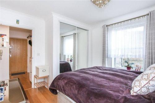 a bedroom with a purple bed and a mirror at Lovely 1 bedroom flat in Richmond-great location! in Richmond upon Thames