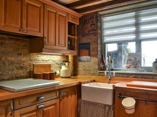 a kitchen with wooden cabinets and a sink and a window at Second Cottage in Cottingham