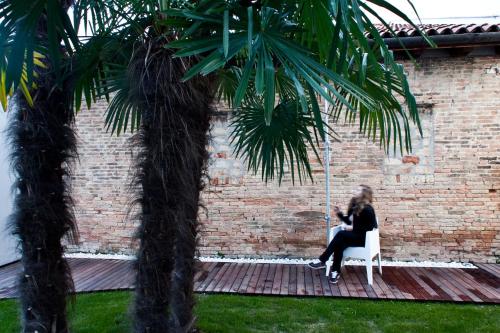 a woman sitting on a swing between two palm trees at Legrenzi Rooms in Mestre