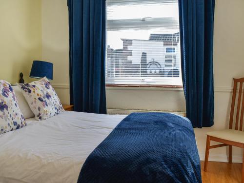 a bedroom with a bed and a window with blue curtains at Why Not in Canterbury