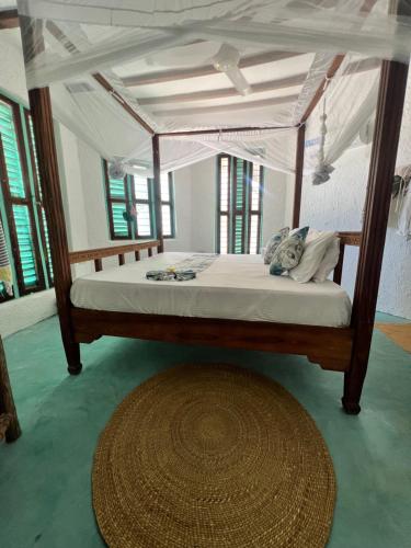 1 dormitorio con cama con dosel y alfombra en Duara Beach House en Paje