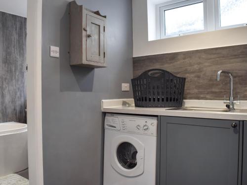 a laundry room with a washing machine and a sink at Gatesgarth in Longton