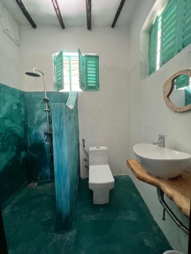 a bathroom with a white toilet and a sink at Duara Beach House in Paje