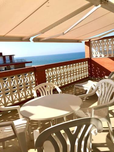 a balcony with white tables and chairs and the ocean at Ático con vistas al mar in Punta Umbría