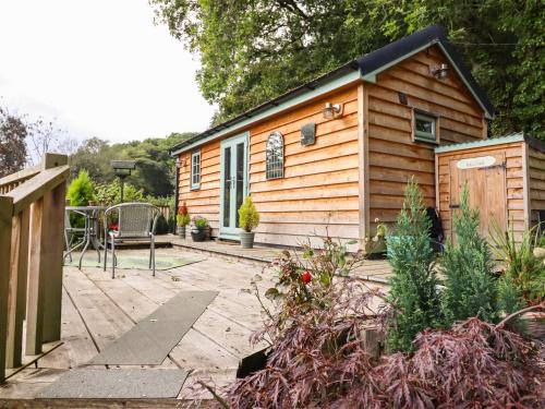 a small wooden cabin with a patio in front of it at Chateau Petit in Caersws