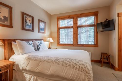 ein Schlafzimmer mit einem Bett und zwei Fenstern und einem Fernseher in der Unterkunft Cabins 1 in Mammoth Lakes