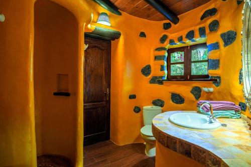 ein orangefarbenes Badezimmer mit einem Waschbecken und einem WC in der Unterkunft Casa La Concha in La Asomada
