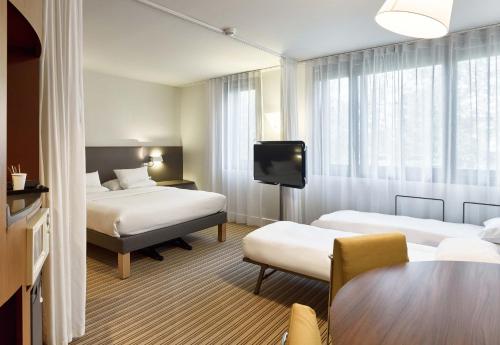 ヴェリジー・ヴィラクブレーにあるB&B HOTEL Vélizy Estのベッド2台とテーブルが備わるホテルルームです。