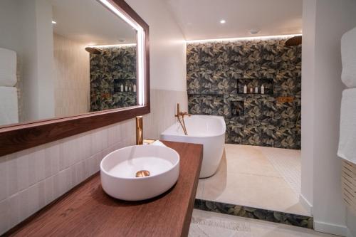 a bathroom with a large white bowl sink and a tub at Hôtel Les Frères Ibarboure in Bidart