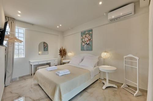 a white bedroom with a bed and a desk at Modern Family apartment Ewa with pool, dining area on Crete coast in Stavromenos